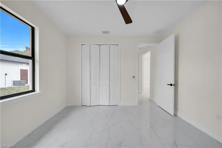 Unfurnished bedroom featuring light marble finish flooring, a ceiling fan, and a closet