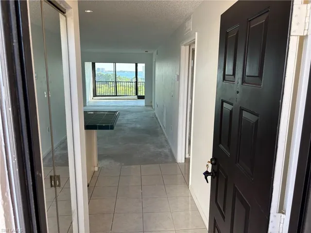 Corridor with light tile patterned floors and a textured ceiling