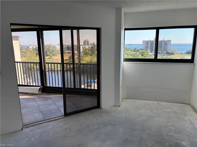 Empty room with a water view, concrete floors, and a textured ceiling