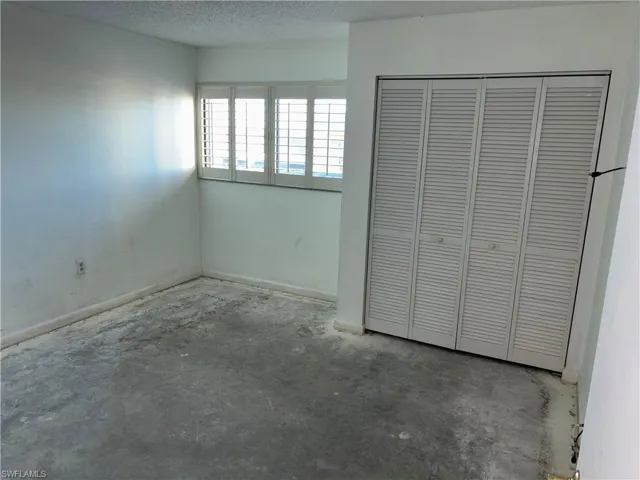 Unfurnished bedroom with a closet, concrete floors, and a textured ceiling