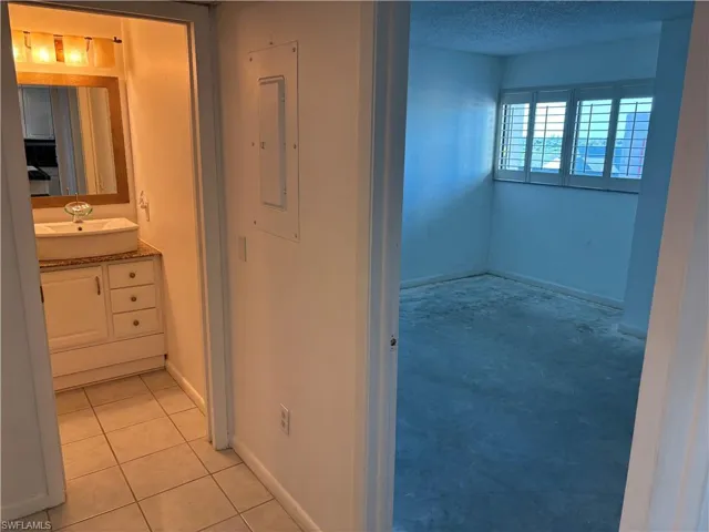 Bathroom with vanity, tile patterned floors, a textured ceiling, and electric panel
