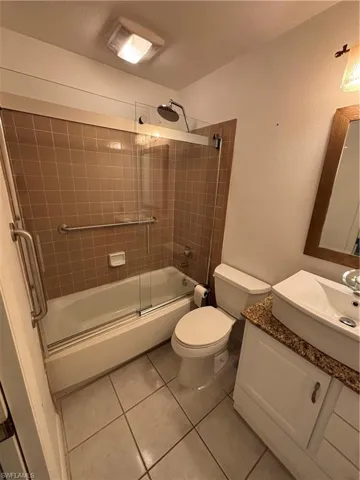 Full bathroom featuring vanity, tile patterned flooring, shower / bath combination with glass door, and toilet