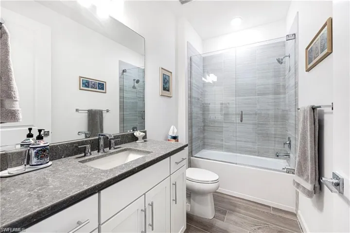 Full bath with vanity, dark wood finished floors, and enclosed tub / shower combo