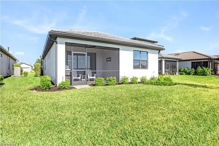 Back of property with a sunroom, a yard, and stucco siding