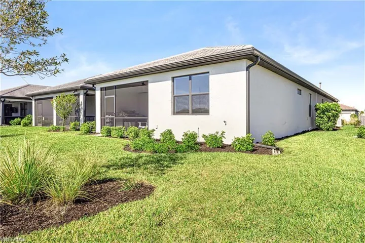 Rear view of property with a sunroom, a yard, and stucco siding