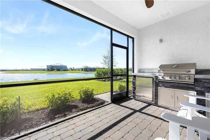 Unfurnished sunroom featuring an outdoor kitchen, a water view, vaulted ceiling, and a ceiling fan