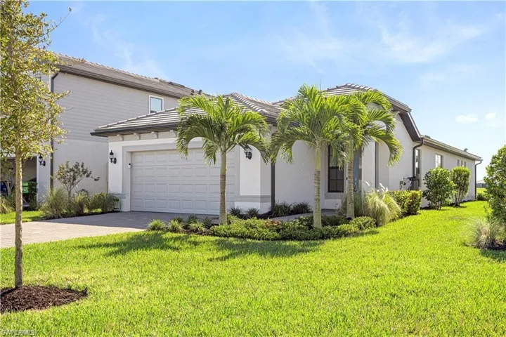 View of front of property with stucco siding, driveway, a garage, and a front yard