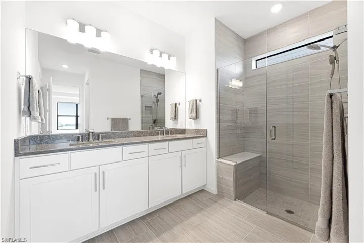 Bathroom with double vanity, a shower stall, and recessed lighting