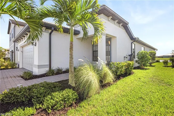 View of side of home featuring stucco siding, an attached garage, and driveway