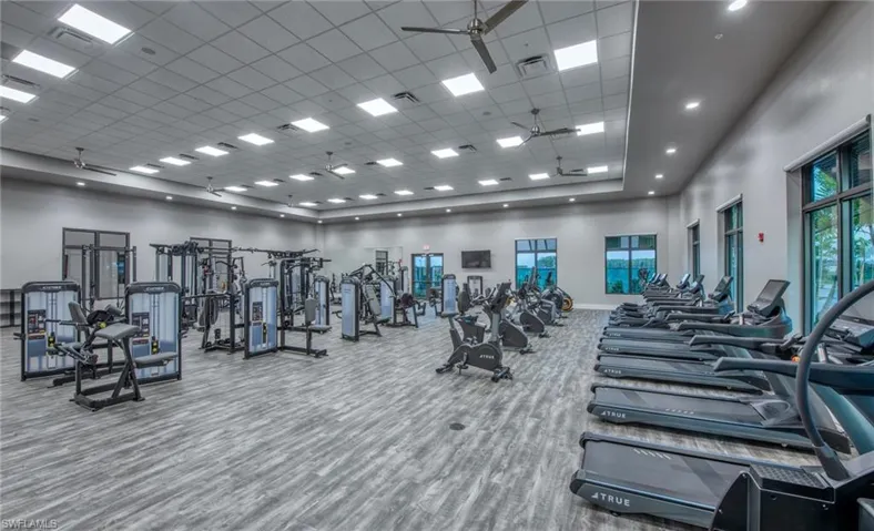 Exercise room featuring a ceiling fan and a high drop ceiling