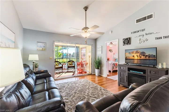 Living room featuring lofted ceiling, a fireplace, light wood finished floors, and a ceiling fan