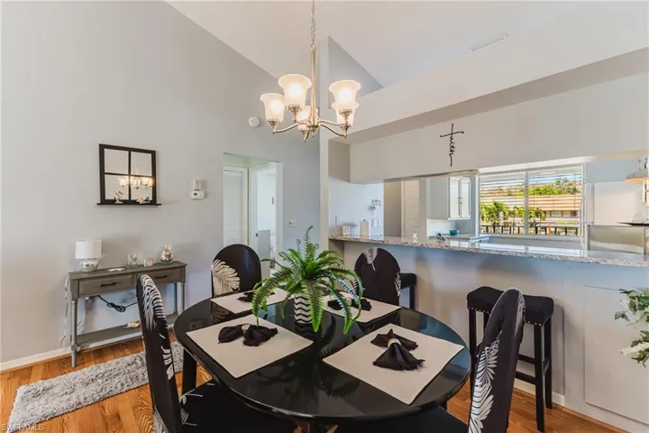 Dining room with light wood-type flooring, a chandelier, and high vaulted ceiling