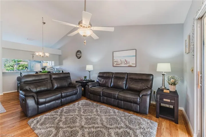 Living room featuring lofted ceiling, ceiling fan, light wood-type flooring, and a chandelier