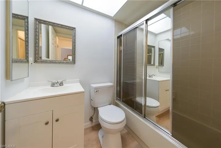 Full bathroom with combined bath / shower with glass door, vanity, and toilet