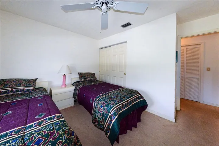 Bedroom with a closet, ceiling fan, and light colored carpet