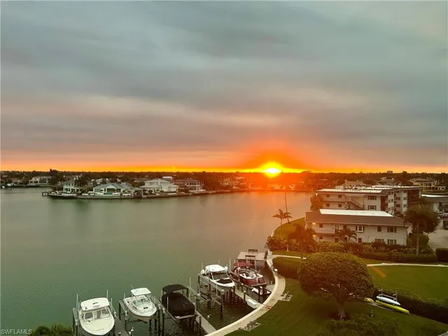 Waterfront exterior featuring a sunset backdrop, boat docks, moored boats, and multi-building complex surroundings
