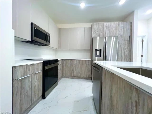 Kitchen with gray cabinetry, appliances with stainless steel finishes, and light tile flooring