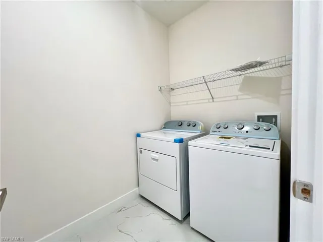 Washroom with washer hookup, washer and clothes dryer, and light tile floors