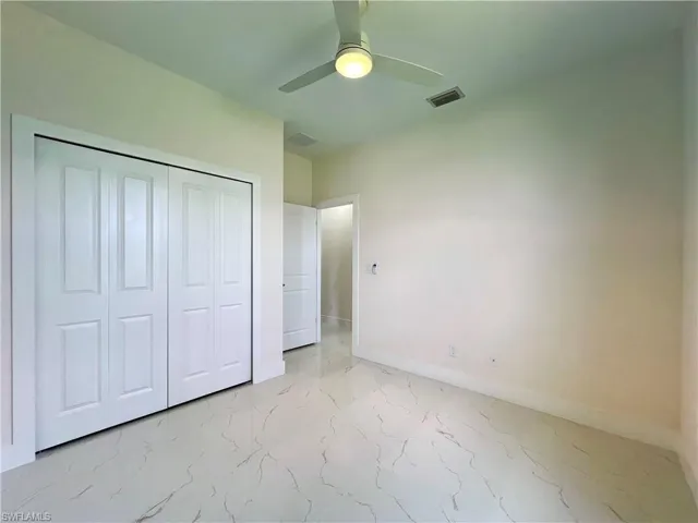 Unfurnished bedroom featuring a closet, light tile flooring, and ceiling fan
