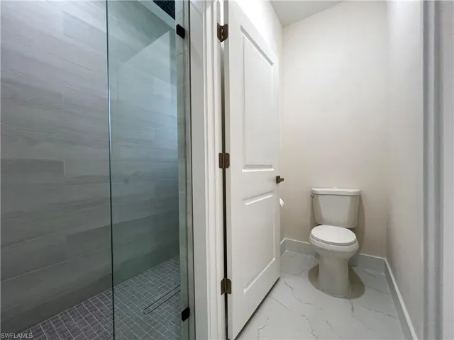 Bathroom with a shower with door, tile flooring, and toilet