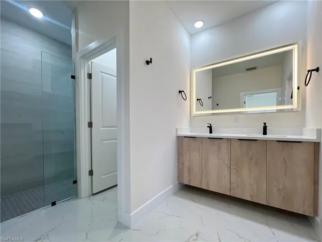Bathroom featuring dual bowl vanity, an enclosed shower, and tile floors