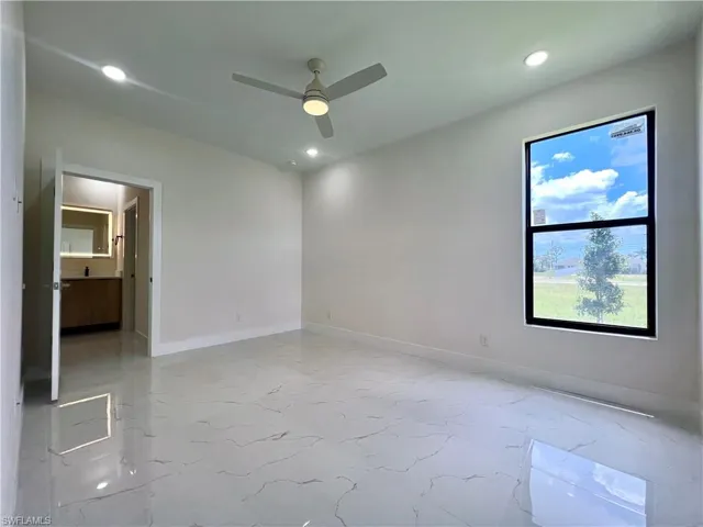 Empty room with ceiling fan and light tile flooring