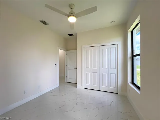 Unfurnished bedroom with a closet, light tile flooring, and ceiling fan