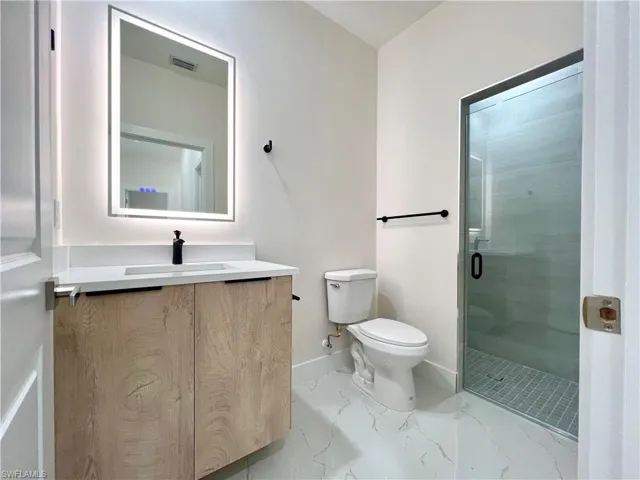 Bathroom with tile floors, walk in shower, toilet, and vanity