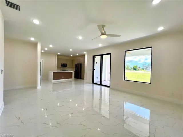 Unfurnished living room featuring light tile flooring and ceiling fan