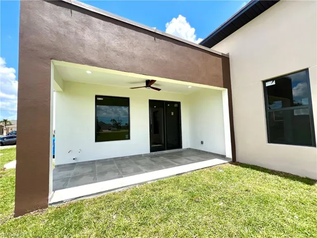 Doorway to property with a yard and ceiling fan