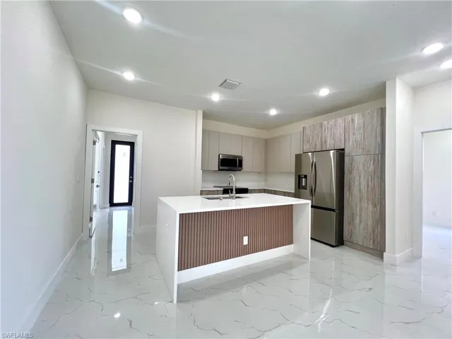 Kitchen with light tile floors, sink, a center island with sink, and stainless steel appliances