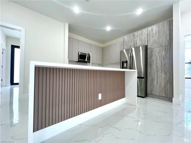 Kitchen featuring gray cabinetry, stainless steel appliances, and light tile flooring