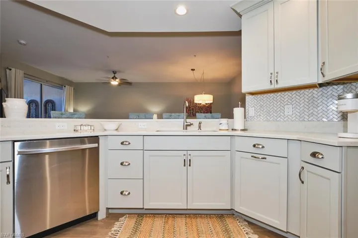 Kitchen with stainless steel dishwasher, backsplash, ceiling fan, light wood-style floors, and open floor plan