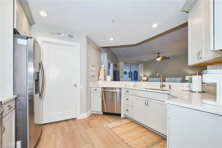 Kitchen with stainless steel appliances, light wood finished floors, white cabinets, a ceiling fan, and recessed lighting