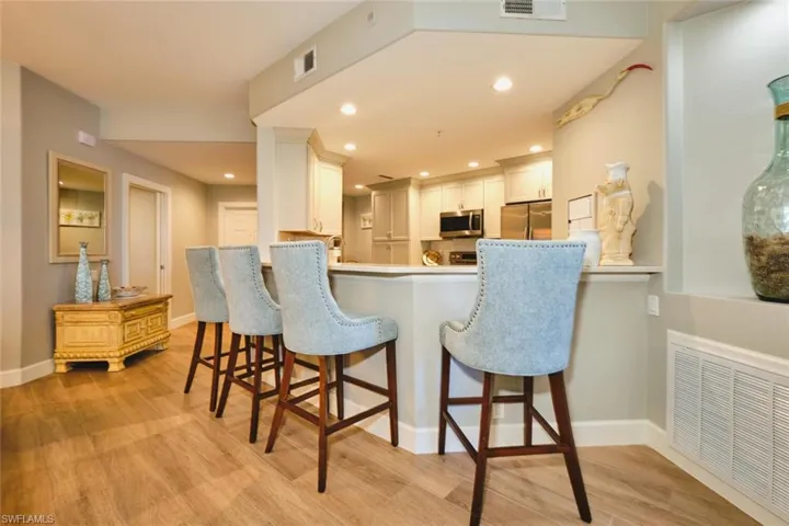 Kitchen featuring white cabinetry, light wood-style floors, appliances with stainless steel finishes, a kitchen bar, and recessed lighting