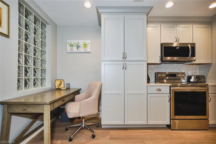 Kitchen featuring stainless steel appliances, light countertops, white cabinets, tasteful backsplash, and light wood finished floors
