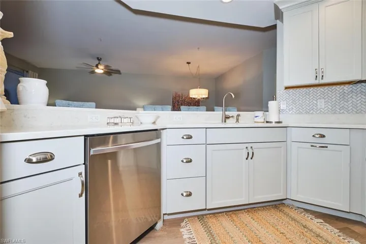 Kitchen with dishwasher, white cabinetry, a ceiling fan, and light stone countertops