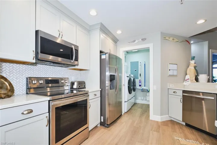 Kitchen with appliances with stainless steel finishes, decorative backsplash, independent washer and dryer, white cabinetry, and recessed lighting
