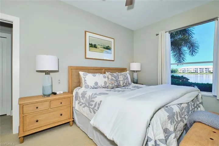 Carpeted bedroom with a water view and ceiling fan