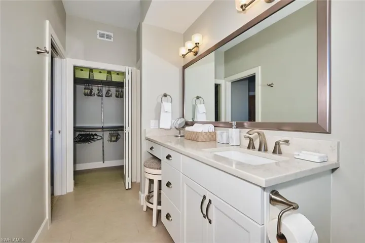 Full bathroom with vanity and a walk in closet