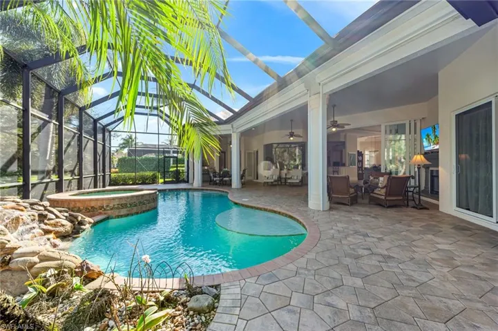 View of pool featuring ceiling fan, a patio, a lanai, and a pool with connected hot tub