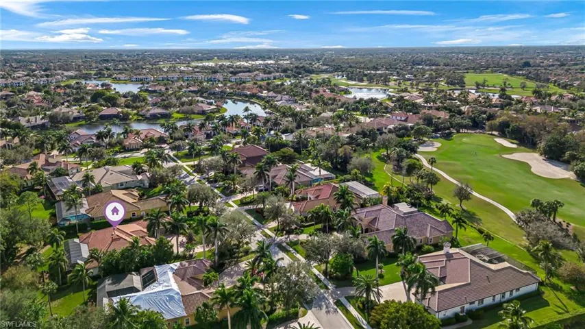Aerial view of property and surrounding area featuring nearby suburban area, a nearby body of water, and a local golf course