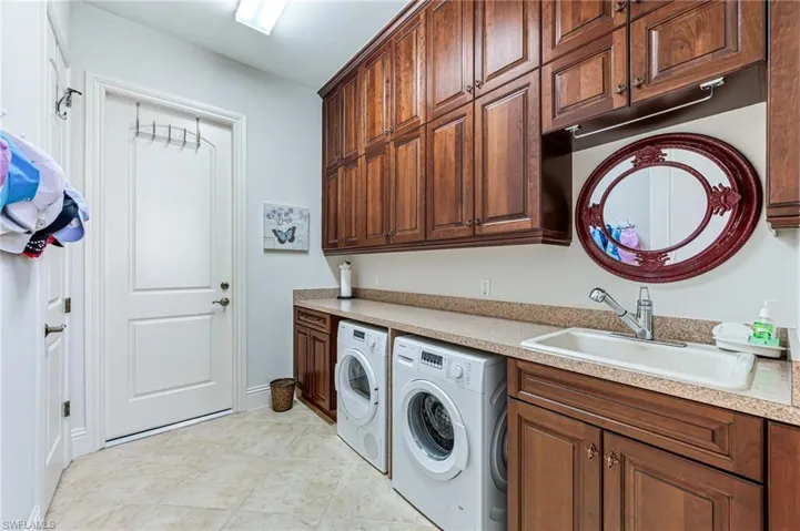 Washroom featuring washer and clothes dryer, cabinet space, and light tile patterned floors
