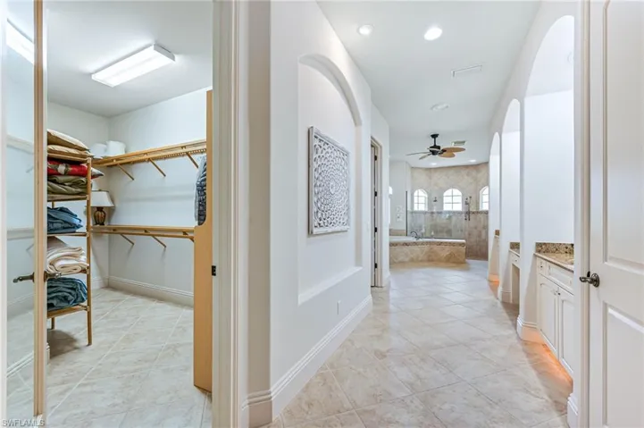 Hallway with light tile patterned flooring, arched walkways, and recessed lighting