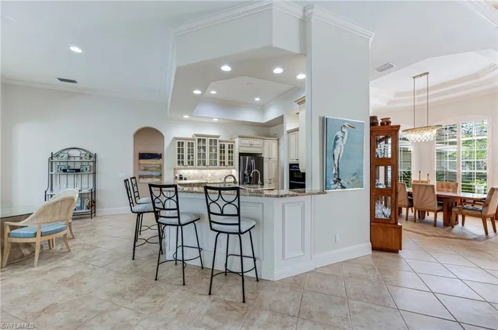 Kitchen featuring stainless steel fridge, cream cabinetry, a chandelier, a tray ceiling, and ornamental molding