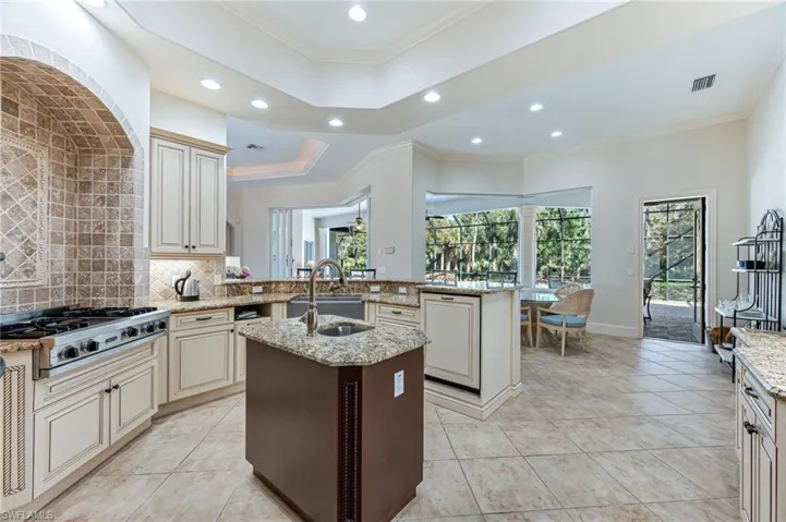Kitchen featuring stainless steel gas stovetop, recessed lighting, a kitchen island with sink, cream cabinetry, and backsplash