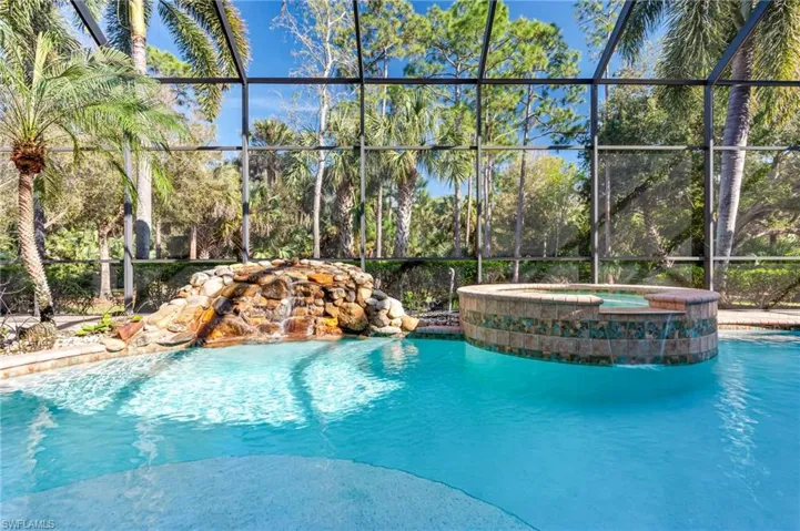 View of swimming pool with a lanai and a pool with connected hot tub