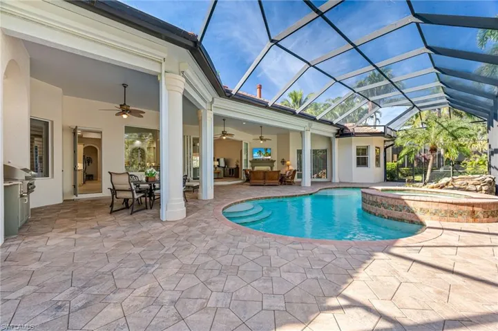 View of pool with ceiling fan, an outdoor living space, a patio area, outdoor dining area, and glass enclosure