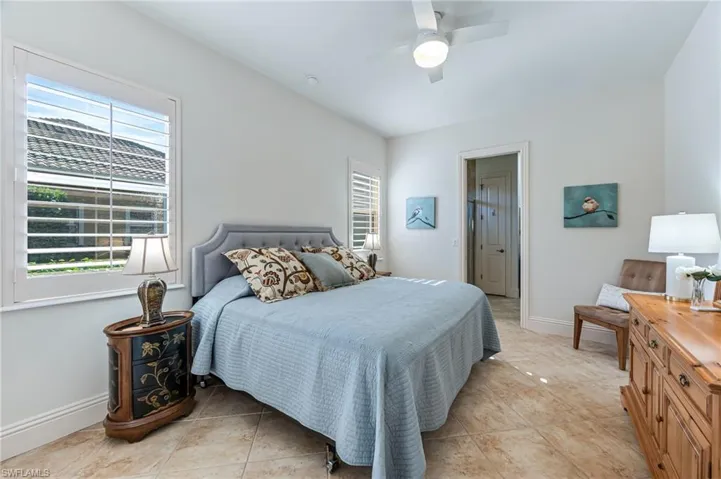Bedroom with multiple windows, light tile patterned floors, and a ceiling fan