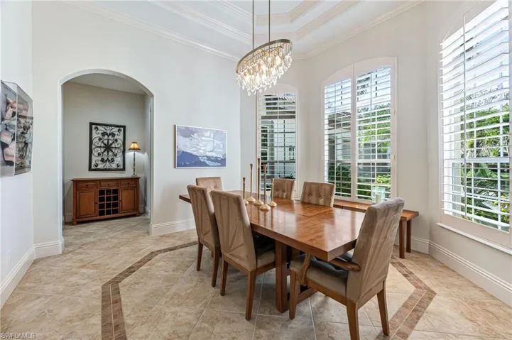 Dining area with inlaid floor details, crown molding, plenty of natural light, and arched walkways